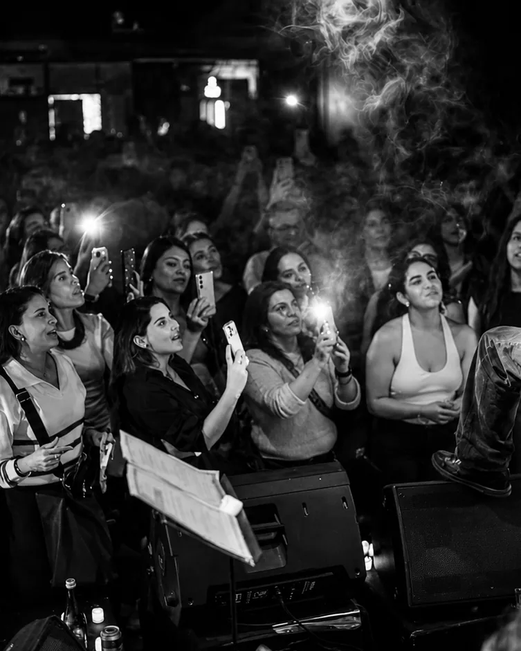 Público en blanco y negro con las caras iluminadas por las linternas de sus teléfonos